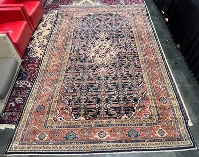 un tapis posé à même le sol dans une pièce où se trouvent des canapés rouges