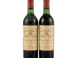 two bottles of red wine sitting next to each other on a white surface