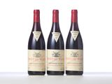 three bottles of red wine are lined up on a table