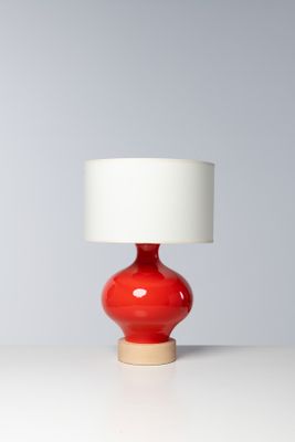 une lampe de table rouge avec un abat-jour blanc, posée sur une table blanche