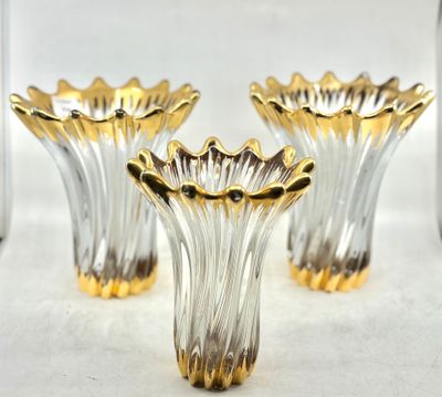 trois vases en verre doré posés sur une table blanche