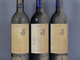 trois bouteilles de vin posées sur une table l'une à côté de l'autre