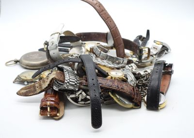 une pile de montres de différents modèles posées sur une surface blanche