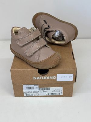 les chaussures de bébé se trouvent dans une boîte posée sur une surface blanche
