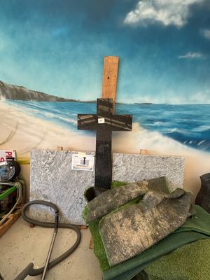 une peinture représentant une croix sur le mur, à côté d'un tas de pierres