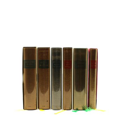 quatre livres sont alignés sur une surface blanche