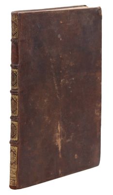 un vieux livre à la couverture brune posé sur une surface blanche