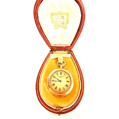 une montre en or dans un écrin rouge sur fond blanc