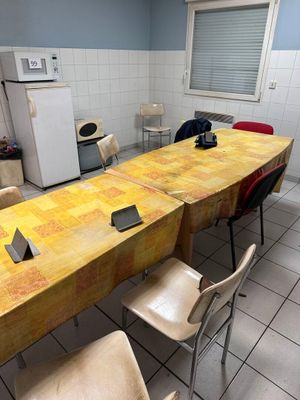 une longue table avec des chaises et un réfrigérateur dans la pièce