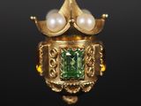 un gros plan sur une bague en or ornée de perles et d'une pierre verte