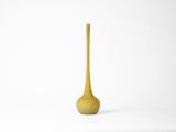 tall yellow vase with a wooden stem on a white background