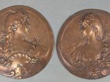 two bronze medallions depicting a woman and a man in profile