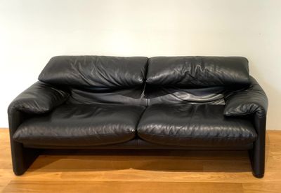 a black leather couch sitting on a hard wood floor