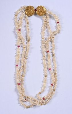 deux rangées de perles blanches entrecoupées de perles rouges et dorées sur un fond blanc