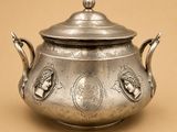 une théière ancienne en argent avec son couvercle, sur fond beige