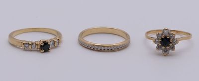 trois bagues en or ornées de diamants noirs et blancs, posées sur un fond blanc