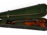 un vieil étui à violon contenant un violon, posé sur une surface blanche