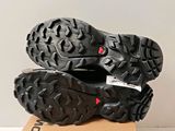 the soles of a pair of black hiking shoes on top of a cardboard box