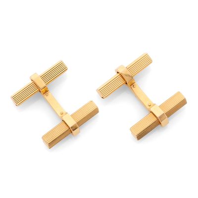 une paire de boutons de manchette plaqués or sur fond blanc