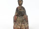statue of a woman sitting on a chair on a white surface