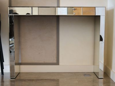a mirror on the side of a desk with a coat rack