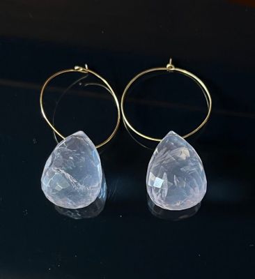 pair of clear quartz earrings with gold hoops on a black surface
