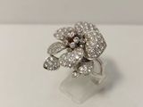 un gros plan d'une bague ornée d'une fleur en diamant posée sur une surface blanche