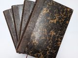 trois vieux livres sont empilés sur une surface blanche