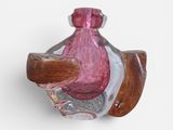 a pink glass bottle with a wooden handle on a wall