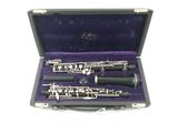 a silver and black clarinet in a purple case