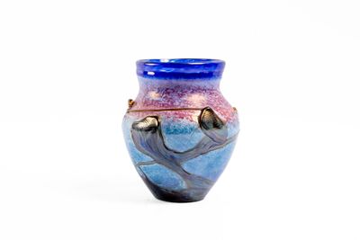 un vase bleu et violet posé sur une surface blanche