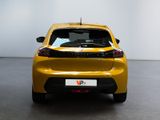 the rear end of a yellow car in a room with a white wall