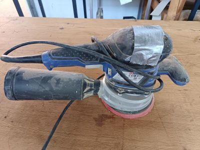 une ponceuse posée sur une table en bois