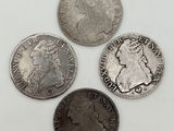 quatre types différents de pièces d'argent sur une surface blanche