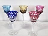 four different colored glass goblets are lined up on a white surface