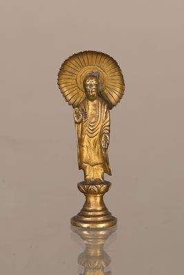 statue en or représentant une personne tenant un éventail, posée sur une table en verre