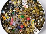 un bol blanc rempli d'une multitude de broches de toutes sortes
