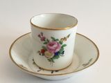 a white cup and saucer with a pink rose on it