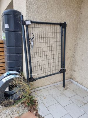 une poubelle posée près d'une clôture, à côté d'un immeuble