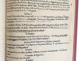 un livre ouvert, sur lequel on voit des inscriptions, posé sur une surface blanche