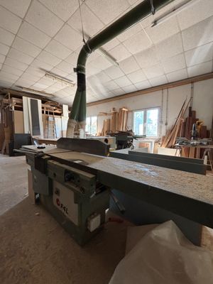 une grande table au milieu d'une pièce, sur laquelle sont posés de nombreux morceaux de bois