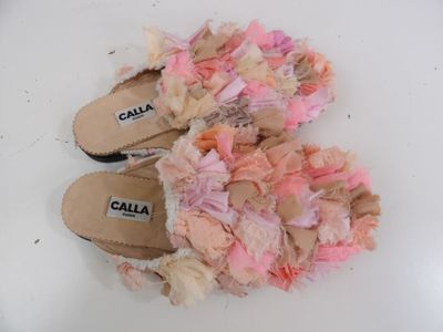 une paire de chaussons roses et blancs posés sur une surface blanche