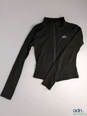 une veste noire portant l'inscription « alo », posée sur une surface blanche