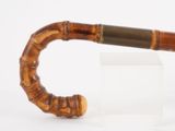 une petite pipe en bois munie d'un manche en bois, posée sur une surface blanche