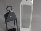 two small white and black lanterns on a table