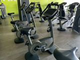 de nombreux vélos d'appartement dans une salle de sport avec un mur vert