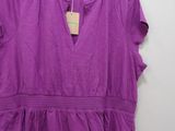 a purple top hanging on a hanger in front of a white wall