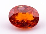 un gros plan d'un saphir orange de forme ovale posé sur une surface blanche
