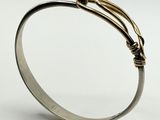 a close up of a silver bracelet with a knot on it