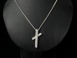 a silver necklace with a cross pendant on a black mannequin